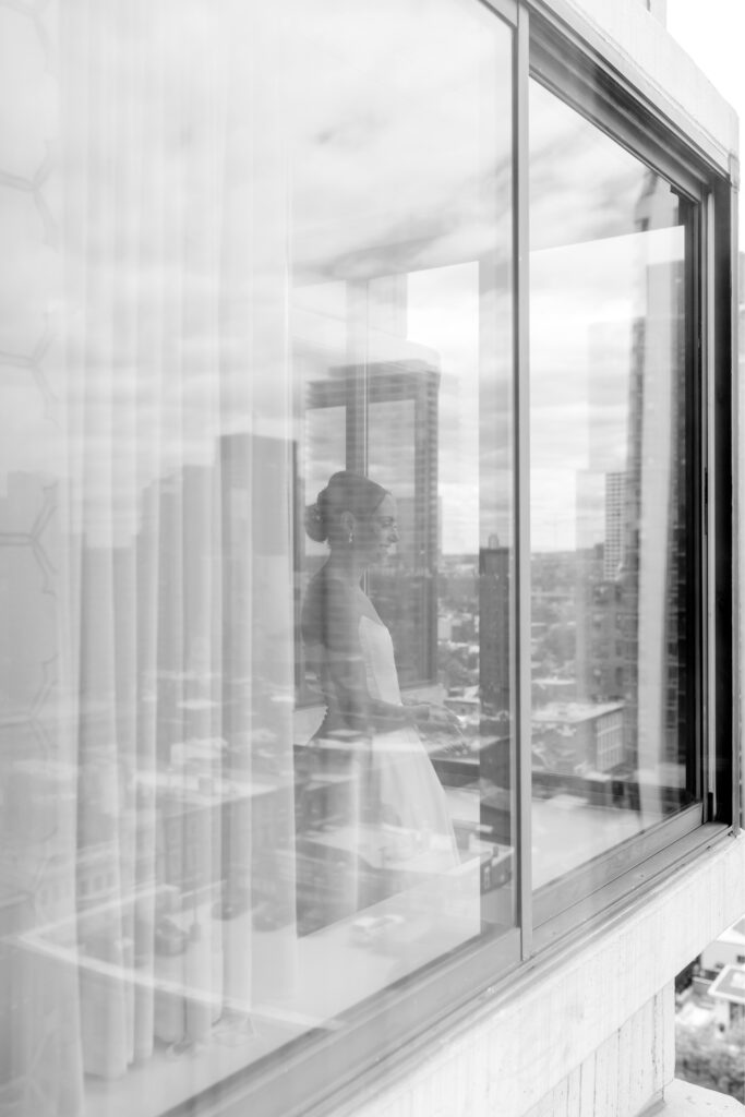 photo of bride through window, with cityscape reflection by Philadelphia wedding photographer Emily Wren Photography