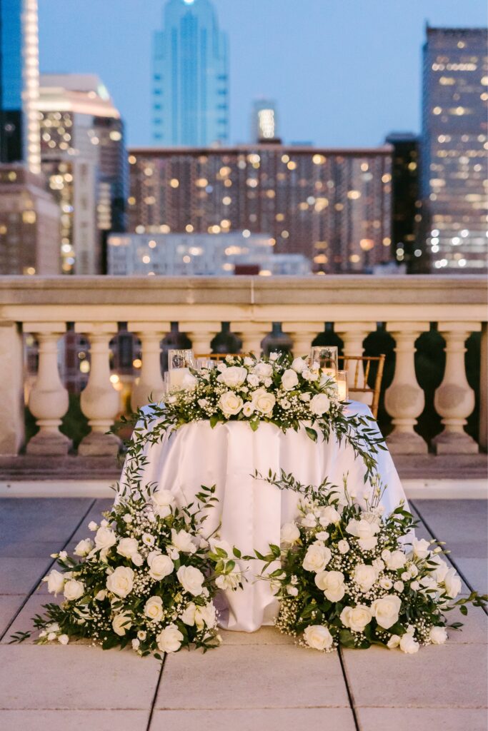 all white floral sweetheart table during summer rooftop wedding reception in Philadelphia