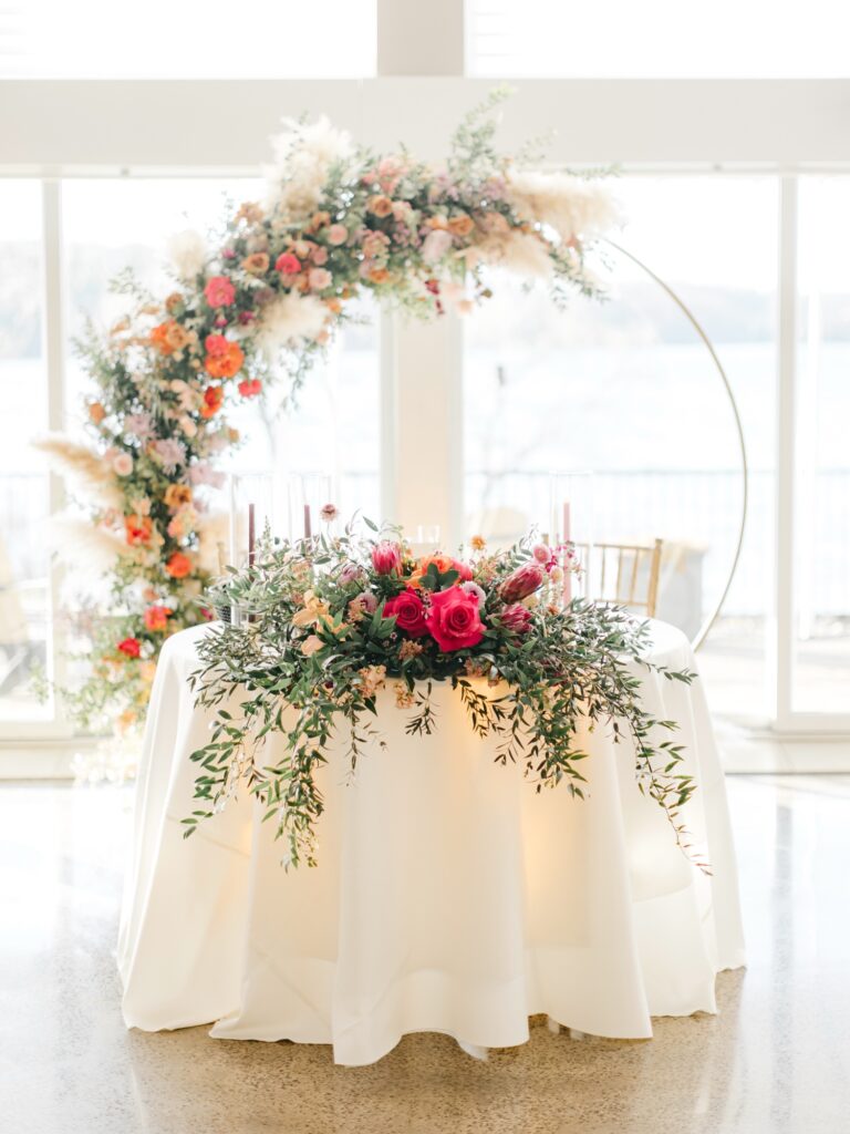 colorful spring floral arch for sweethearts table at wedding reception