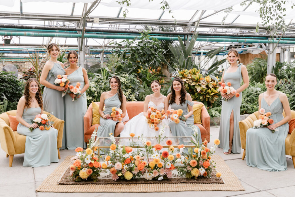 bride with her bridesmaids dressed in faded sage green bridesmaid dresses at Fairmount Horticultural Center