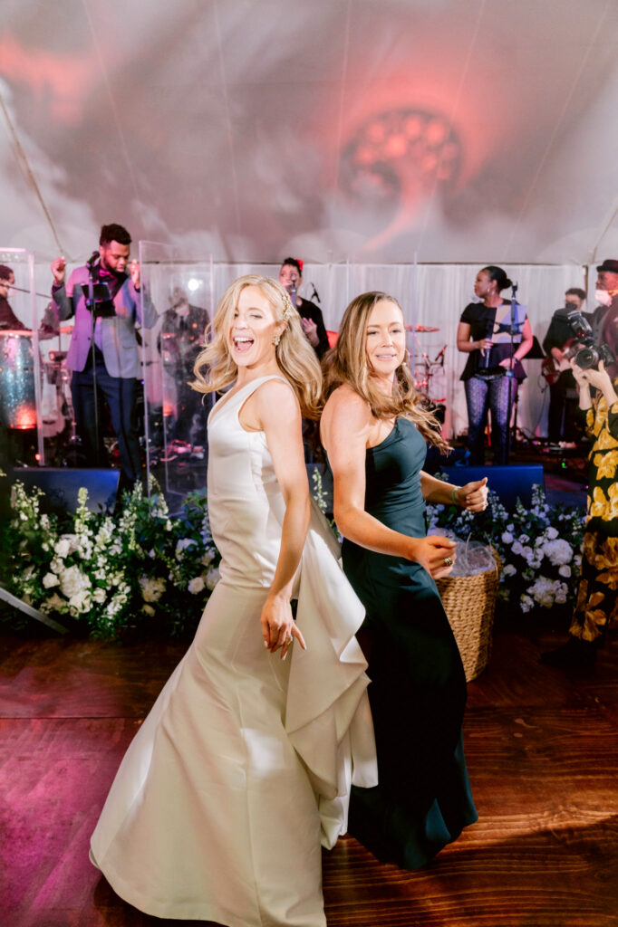 bride dancing & singing with bridesmaid at fun white tented New Jersey wedding reception