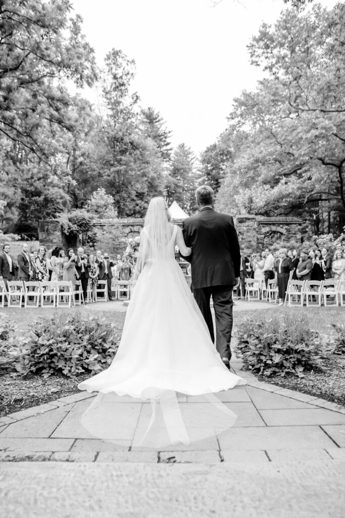 bride walking down the aisle at her outdoor summer garden wedding ceremony