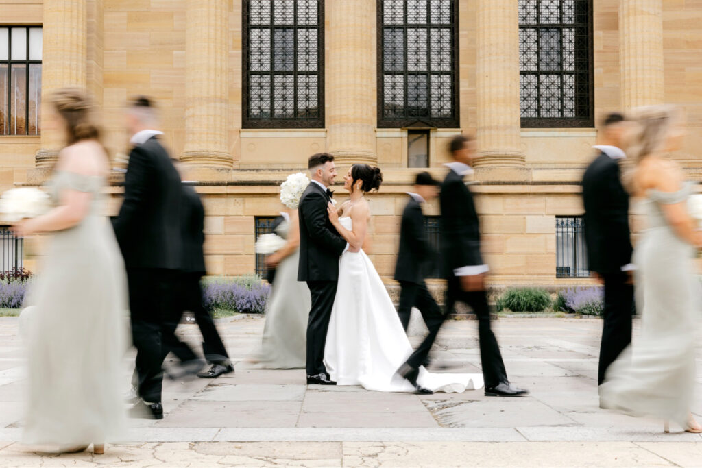 full wedding party walking around bride & groom at the Philadelphia Art Museum by Emily Wren Photography