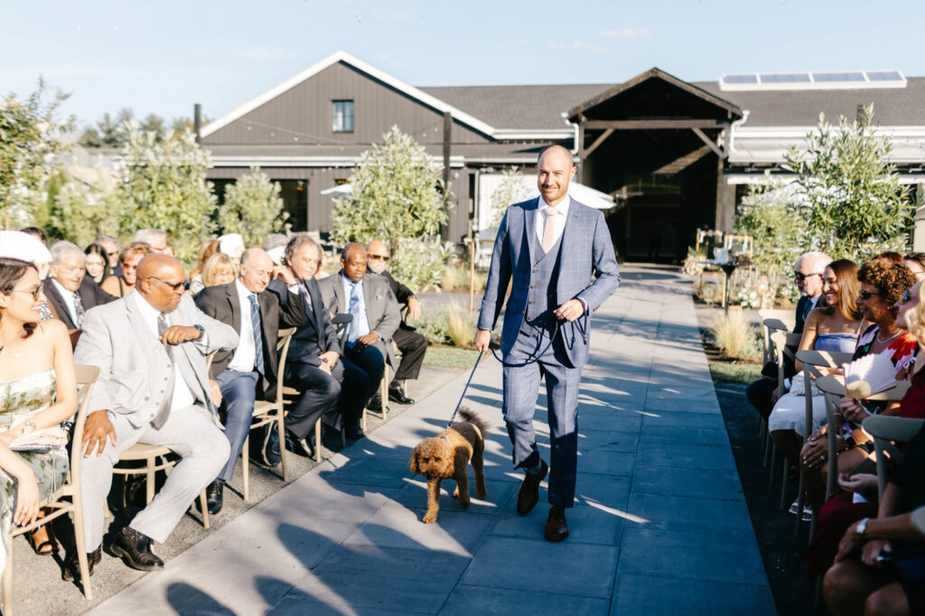 groom walking down the aisle with pet dog