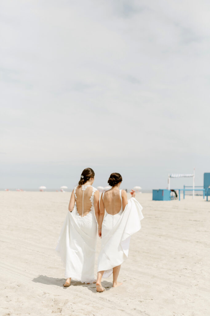 brides walking along the beach in Cape May New Jersey by Emily Wren Photography