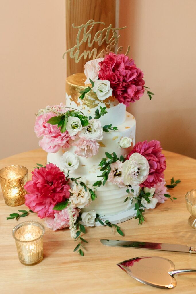 3 tier wedding cake with hot pink florals and gold topper