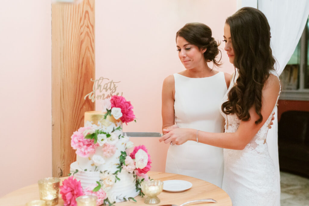 same sex brides cutting their wedding cake at Cape May wedding reception by Emily Wren Photography