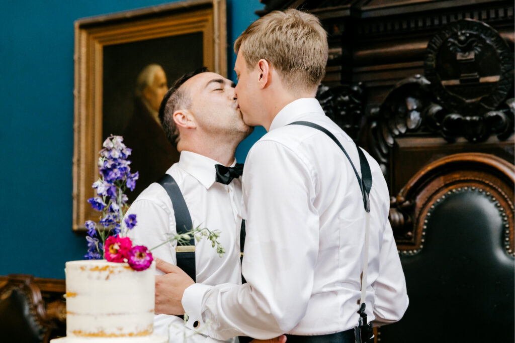 LGBTQ grooms cutting their wedding cake at College of Physicians wedding reception by Emily Wren Photography