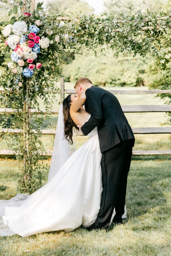 bride & grooms first kiss at outdoor Pennsylvania summer wedding by Emily Wren Photography