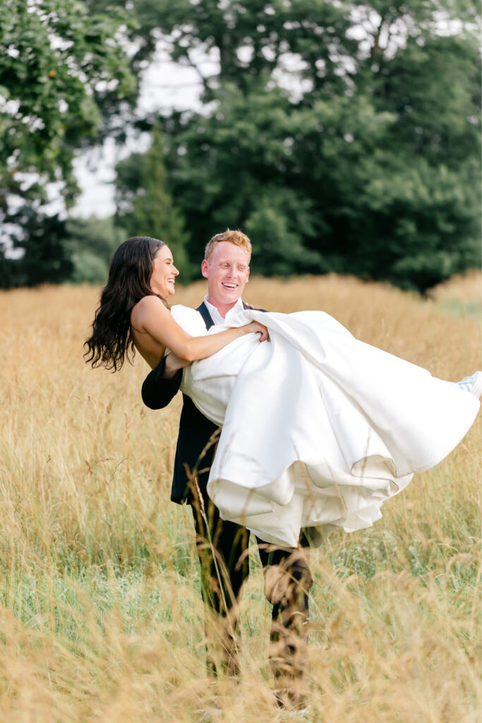 groom carrying the bride through a Pennsylvania field