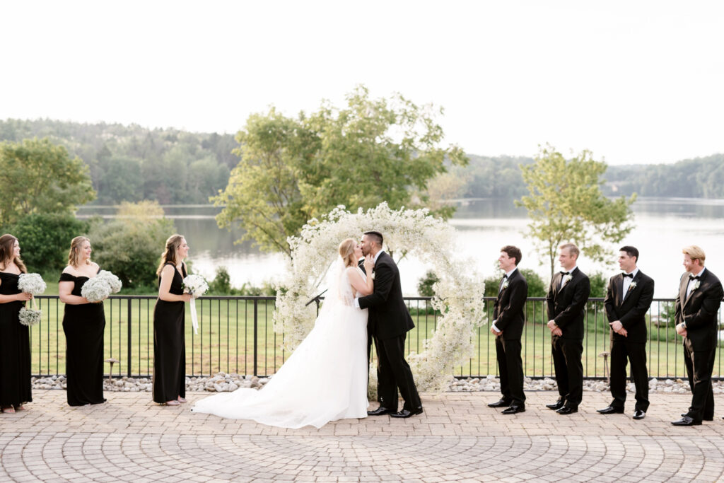 bride & grooms first kiss during outdoor summer lakeside wedding