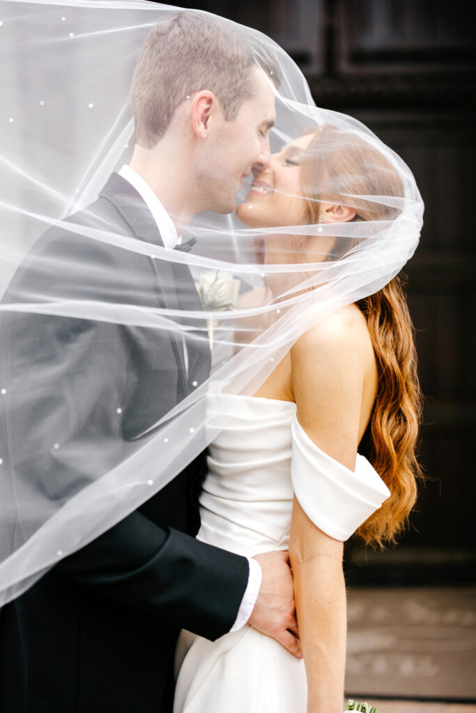 bride & groom kissing under bridal veil by Emily Wren Photography