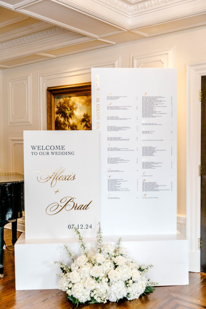 white and gold wedding reception welcome sign and seating chart