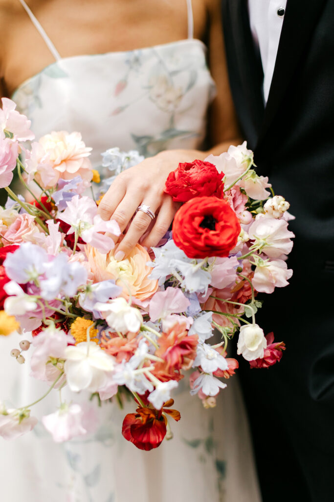 vibrant, colorful summer bridal bouquet filled with red, pink, lilac and ivory flowers