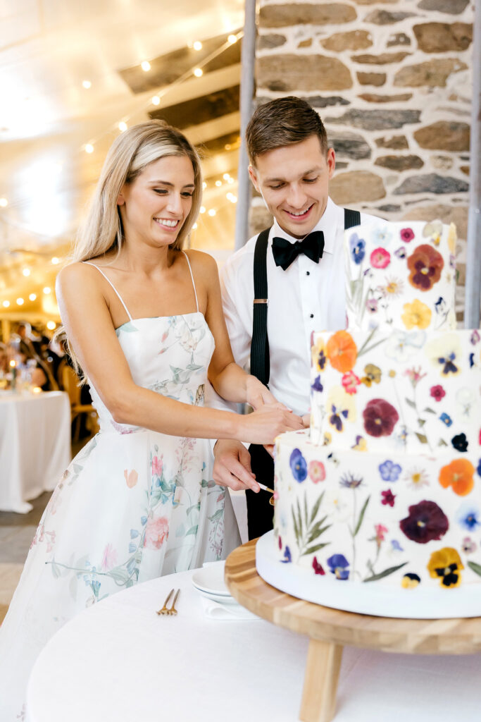 bride & groom cutting their colorful wedding cake with floral pressings