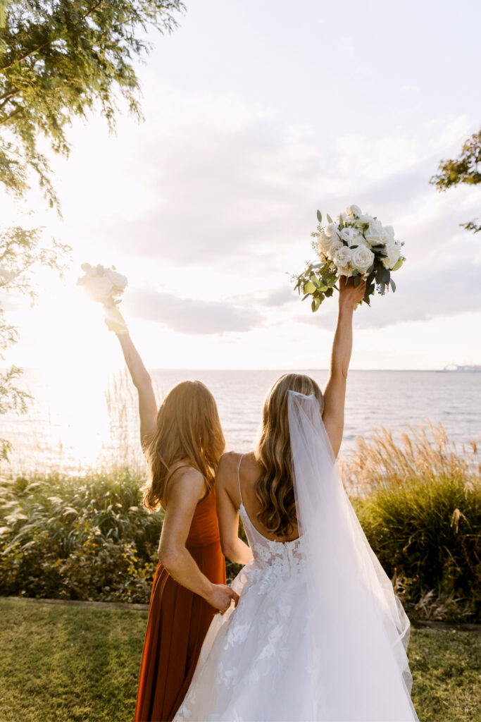 bride & maid of honor looking out onto the water during sunset by Emily Wren Photography