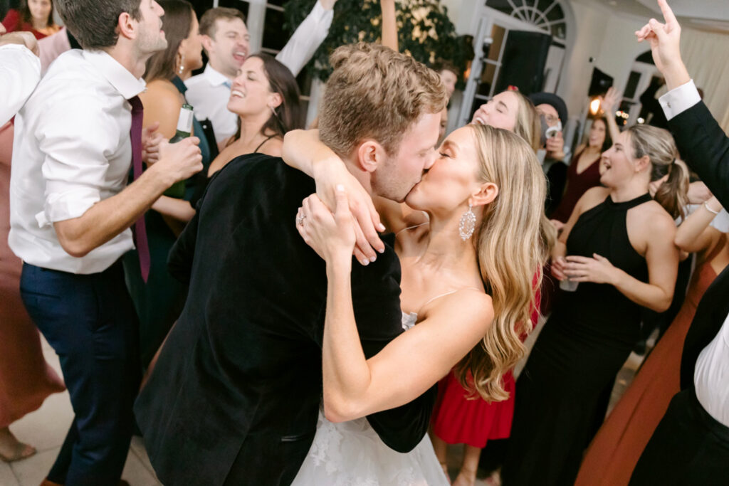 bride & groom kissing as their guests dance around them at Chesapeake Bay wedding reception in Maryland