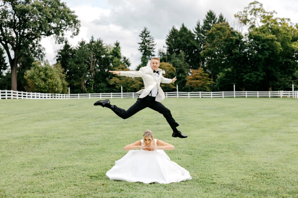 portrait of bride & groom being funny and jumping around on their wedding day by Emily Wren Photography