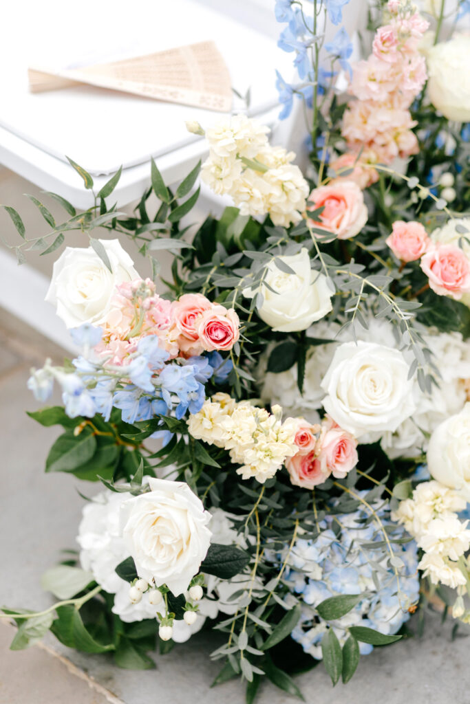 pink, white, ivory and blue summer wedding florals aligning the ceremony aisle