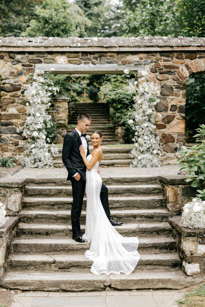 bride & groom portrait in front of white floral arch at Parque Ridley Creek by luxury wedding photographer Emily Wren Photography