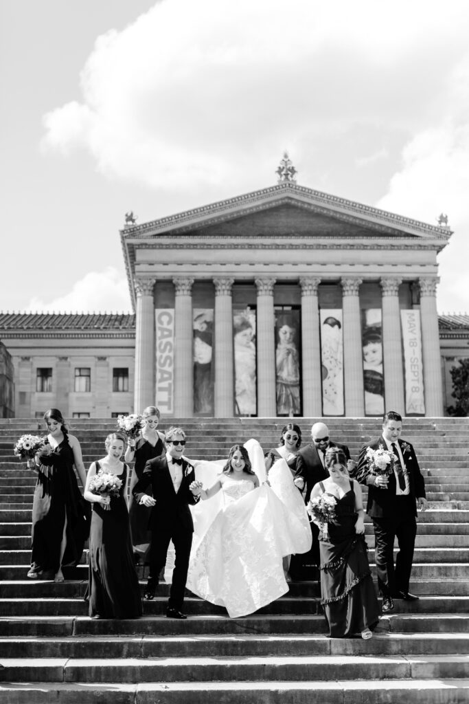 full wedding party walking down the Philadelphia Art Museum steps by luxury wedding photographer Emily Wren Photography