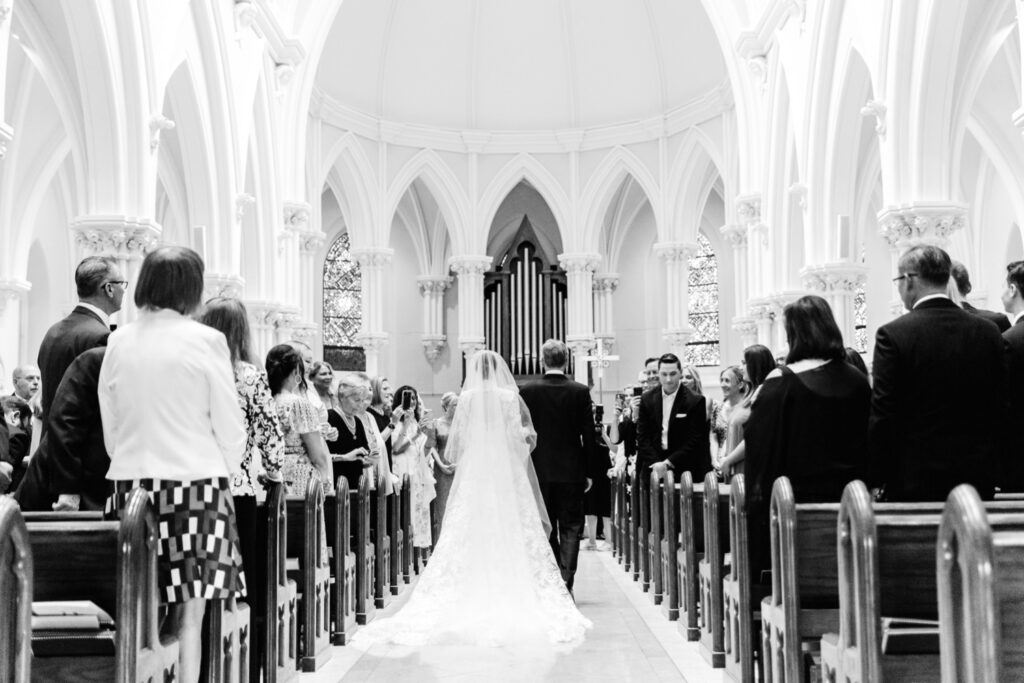 bride walking down the aisle at St. Thomas of Villanova Church by Emily Wren Photography