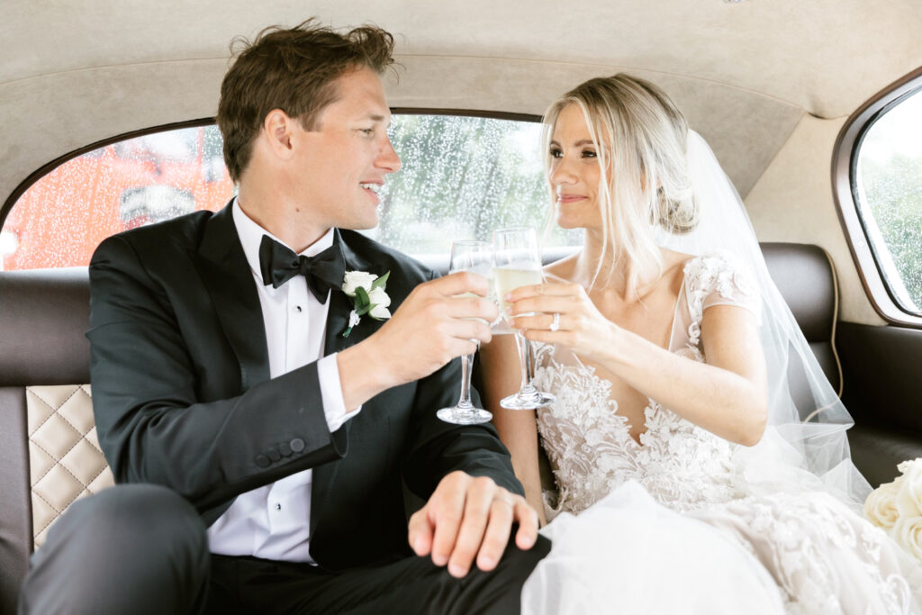 bride & groom drinking champagne after their New Jersey wedding ceremony in a vintage Rolls Royce car