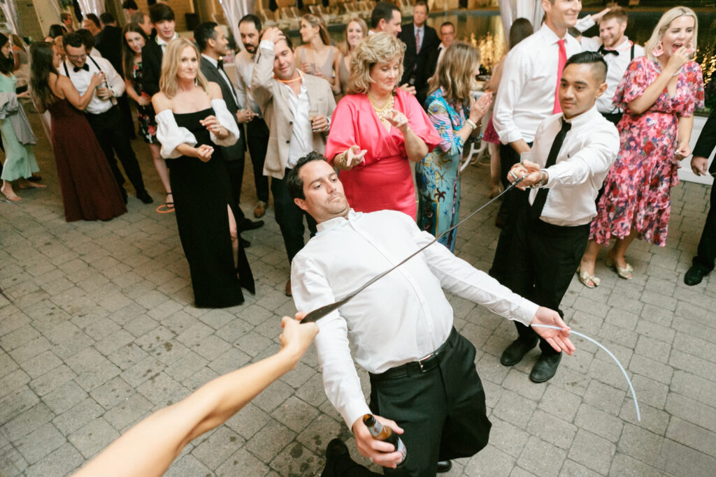 wedding guests playing limbo with a tie at Spring Lake Tennis and Bath club wedding reception by Emily Wren Photography