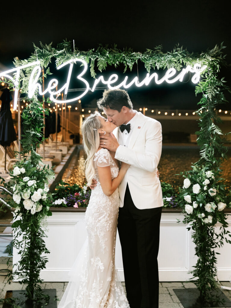 bride & groom kissing in front of an LED sign with their last name by New Jersey wedding photographer Emily Wren Photography