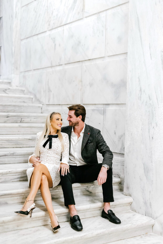 engaged couple sitting on the Ritz Hotel steps by Emily Wren Photography