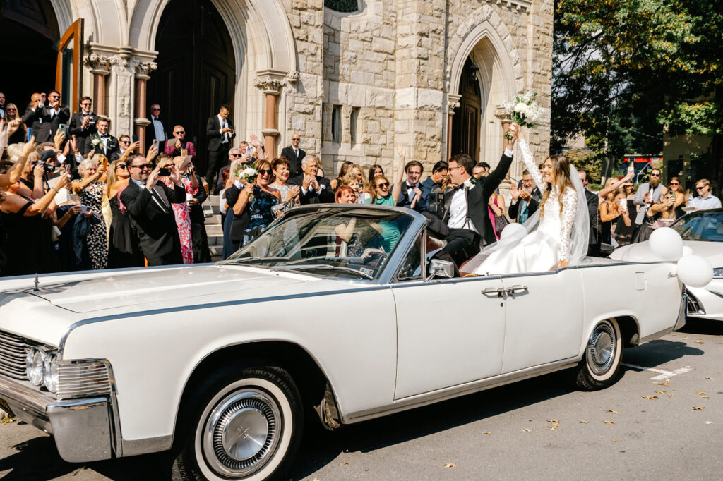 bride & groom exiting their church wedding ceremony in a vintage car