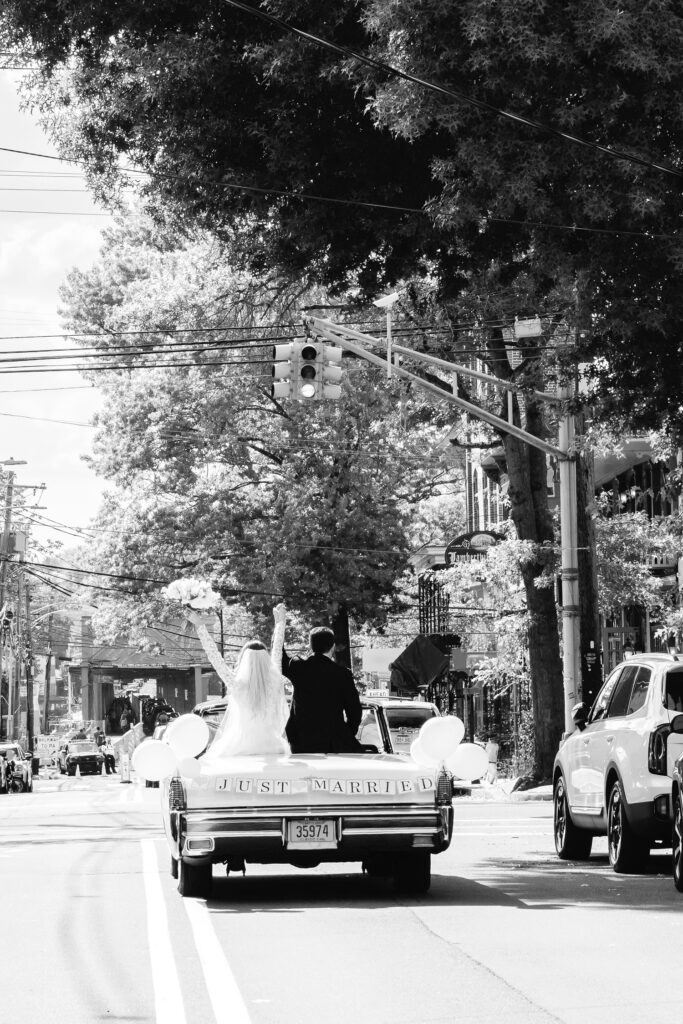 bride & groom leaving their wedding ceremony in a vintage car with a "just married" banner by Emily Wren Photography