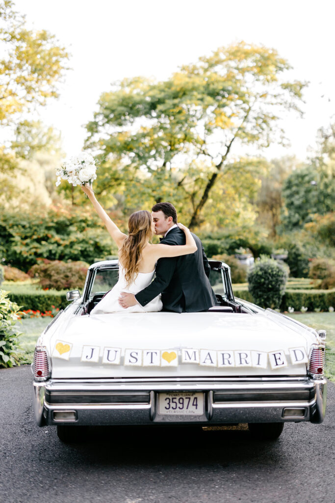 bride & groom kissing in a vintage car, decorated with a just married" banner in New Hope, Pennsylvania