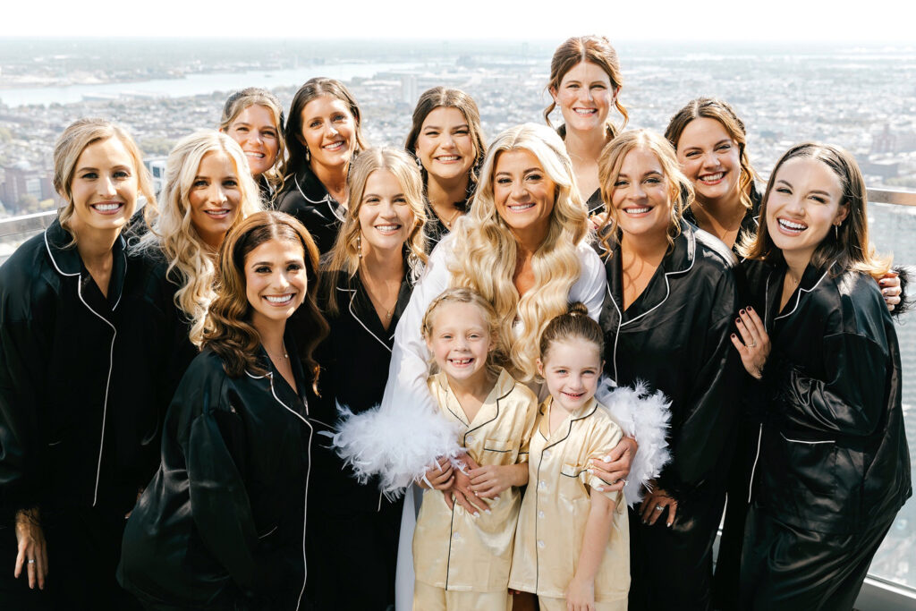 bride with her bridesmaids in matching black and gold silk pajamas on Philadelphia hotel rooftop balcony