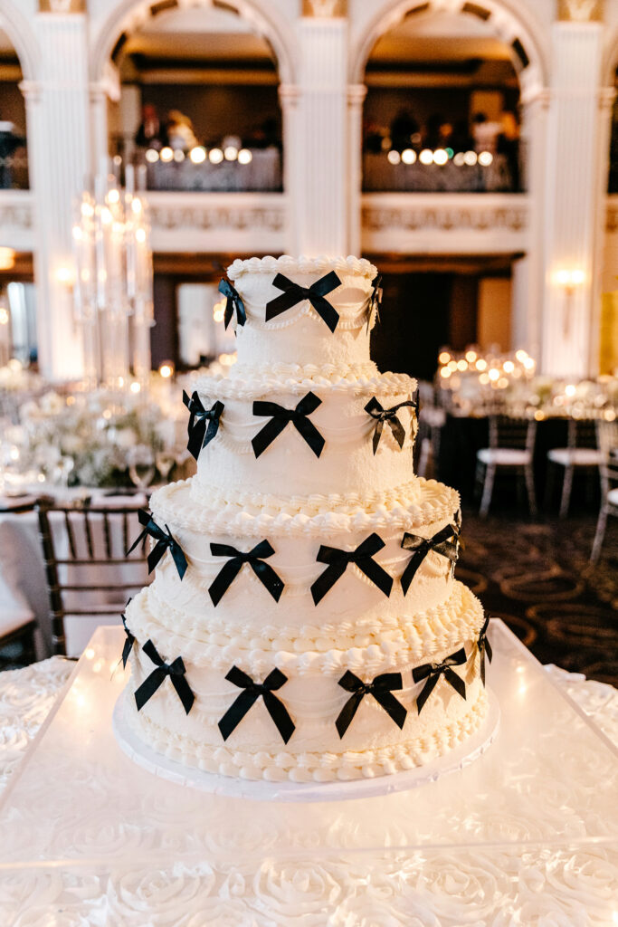 4 tier white wedding cake decorated with black bows by Emily Wren Photography