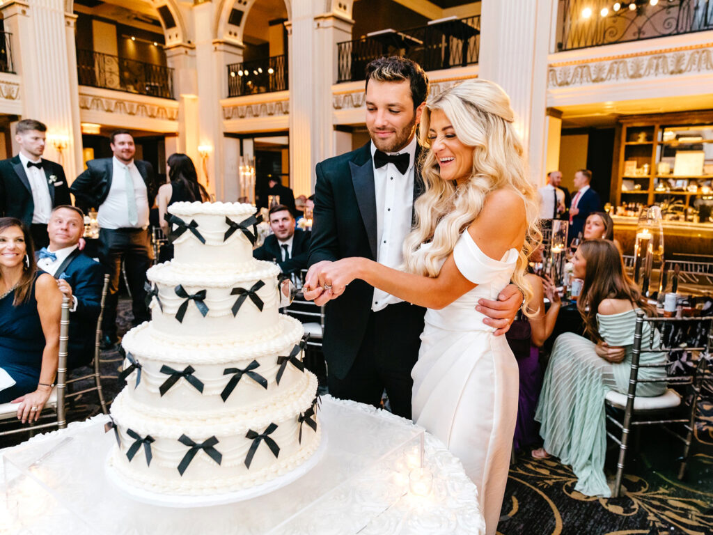 bride and groom cutting their wedding cake decorate with black bows at Center City Philadelphia wedding reception