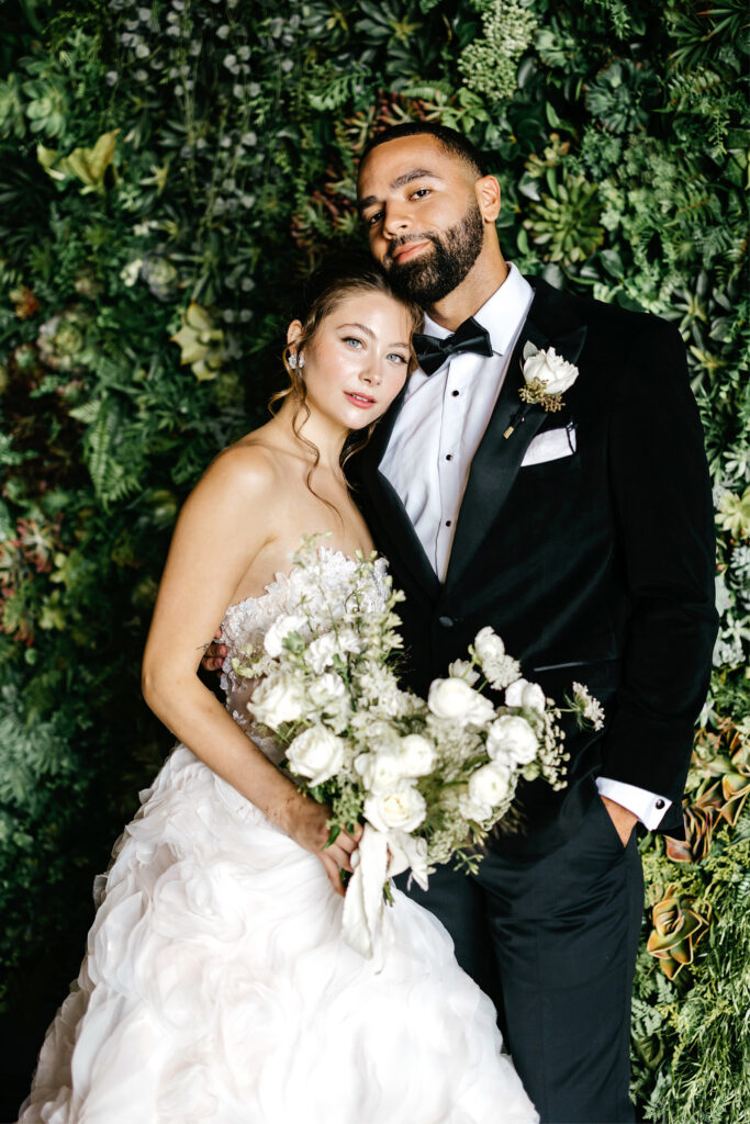 bride and groom portrait in front of Nicol Floral Design photo wall by Emily Wren Photography