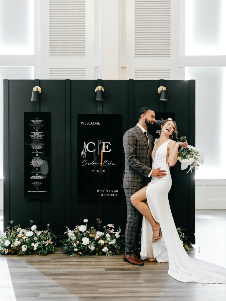 bride and groom in front of their wedding reception seating chart by Nicol Floral Design at The Ivy wedding reception