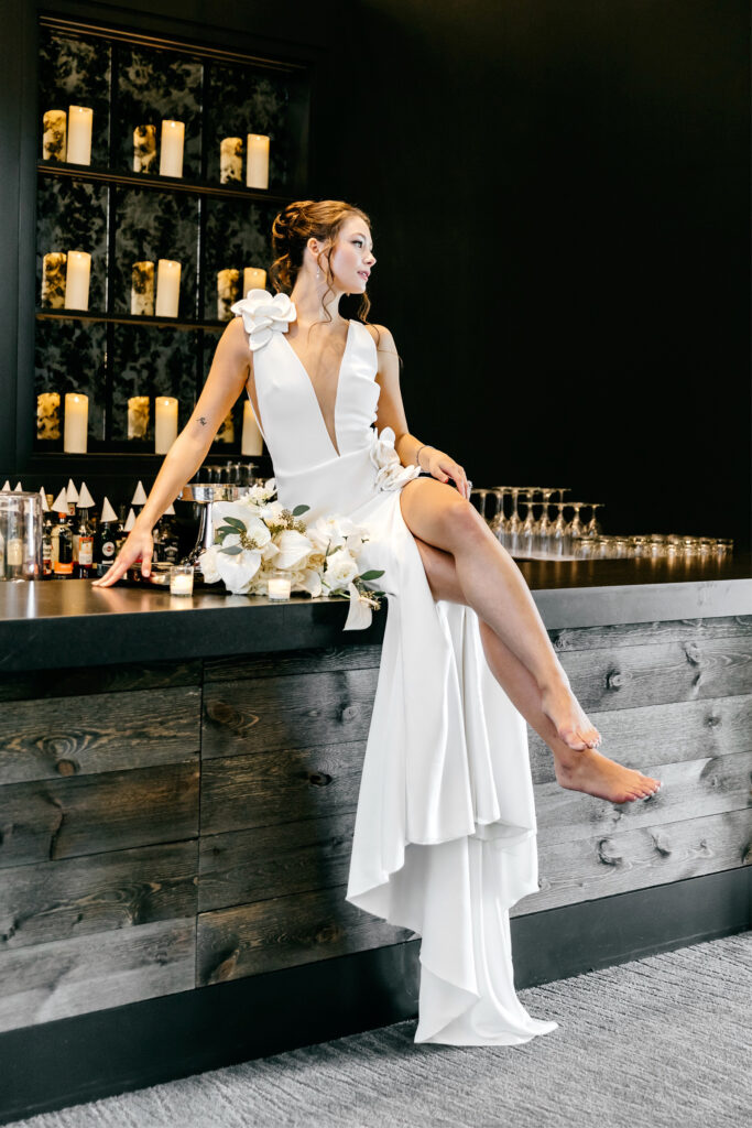 bride sitting on top of bar at The Ivy by Emily Wren Photography