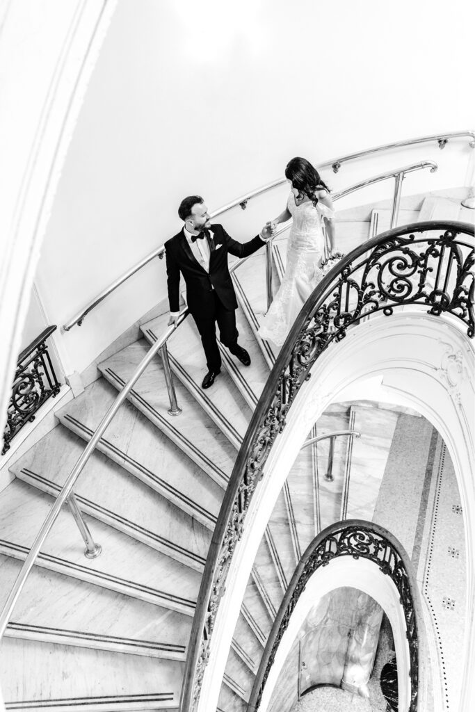 bride & groom walking down spiral staircase at Grand hotel