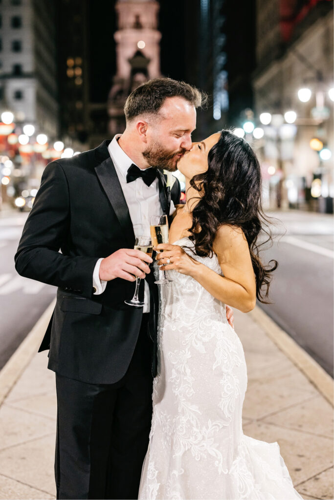 bride & groom kissing on Broad Street in front of City Hall by Emily Wren Photography