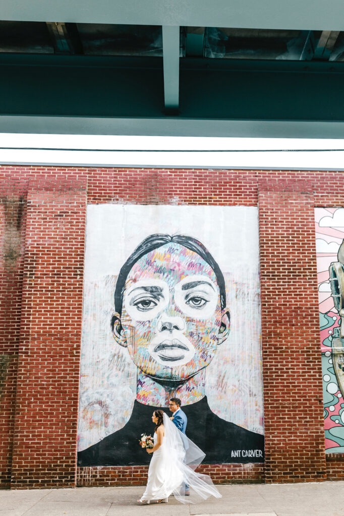 bride and groom walking through Fishtown in front of the murals on November wedding day