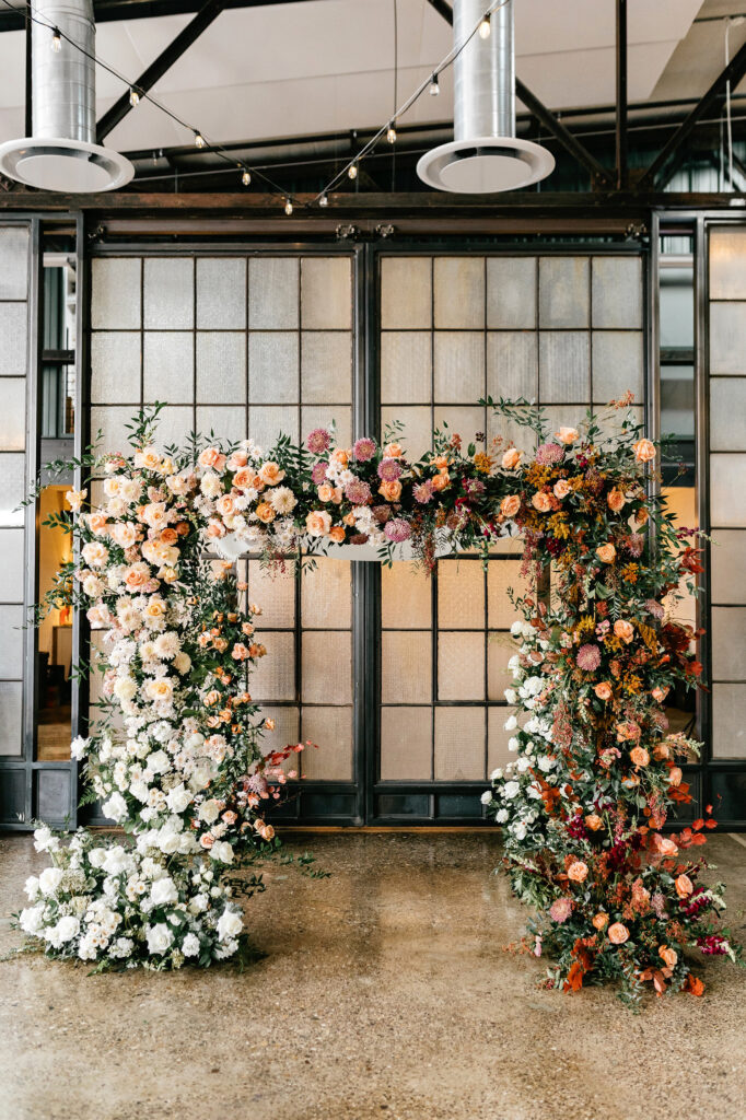 fall floral wedding arch at indoor wedding ceremony