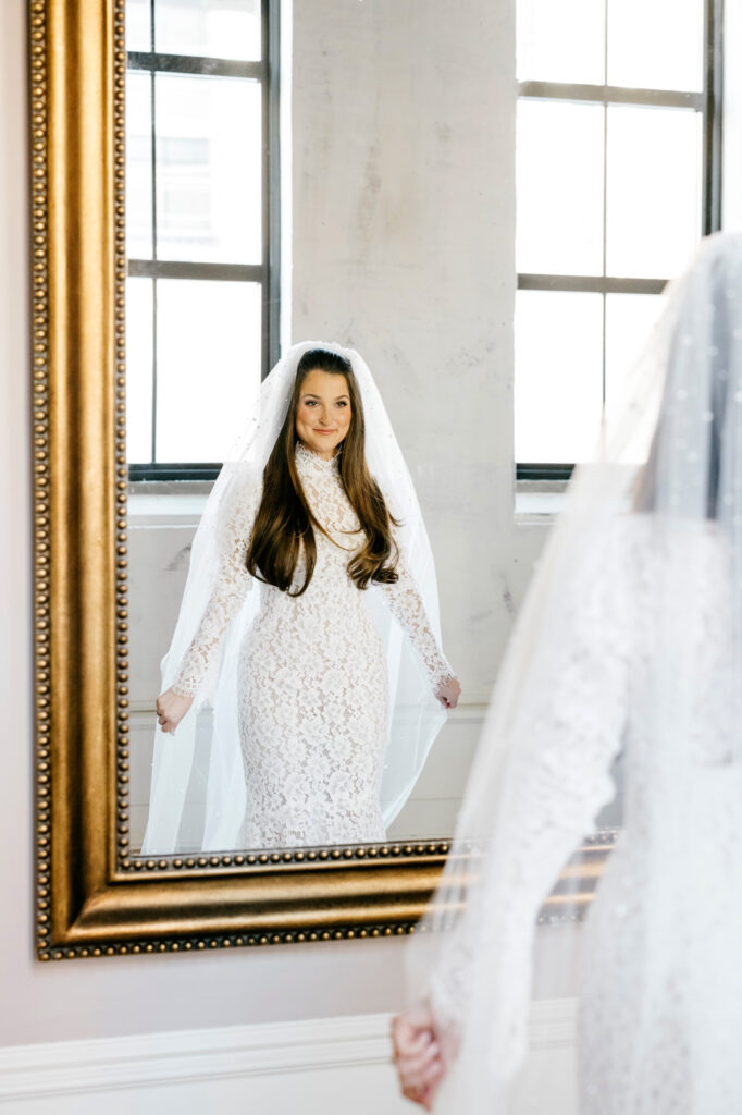 Timeless winter bride looking at herself in the mirror by Emily Wren Photography