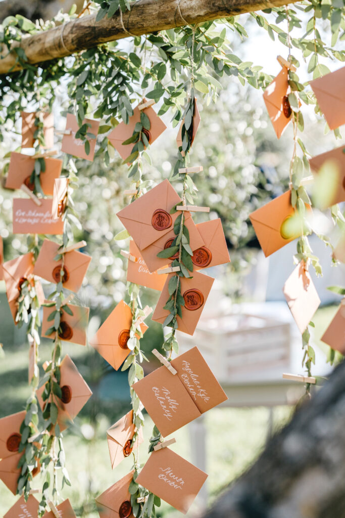 wedding reception seating cards hanging from a vine on a tree