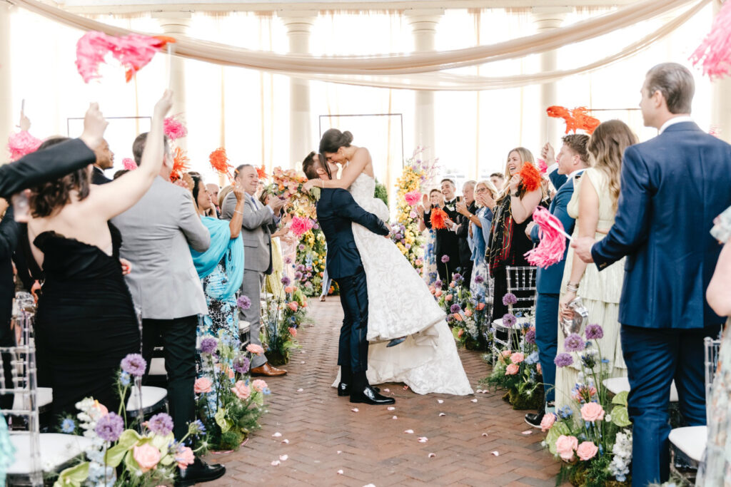 groom lifting and kissing his bride into the air as they exit their Cescaphe Water Works wedding ceremony