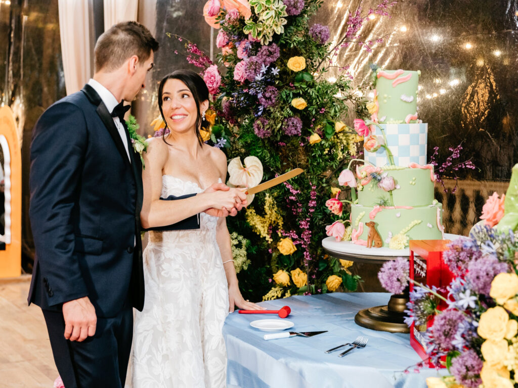 bride & groom cutting their colorful wedding cake at Cescaphe Water Works wedding reception