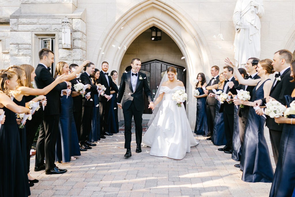 bride & groom exiting St Paul's Catholic Church as their wedding party throws flower petals