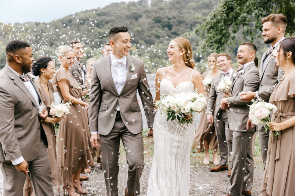bride and groom walking as their wedding party throws flower petals