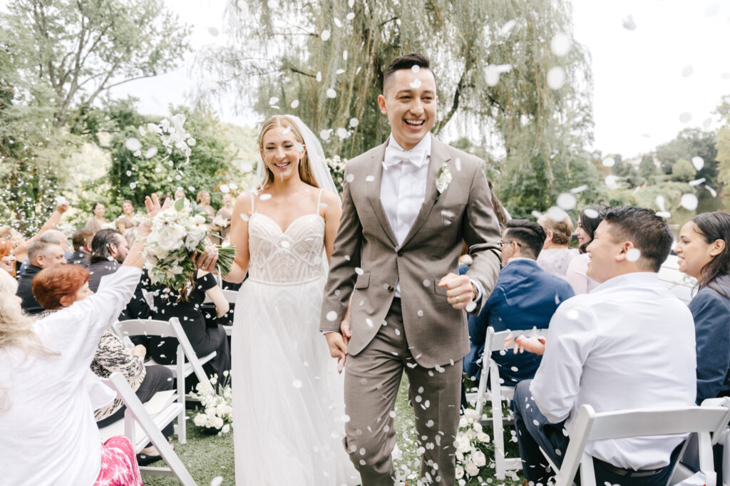 PA bride & groom exiting their outdoor wedding ceremony as their guests throw flower petals